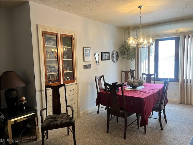 dining area featuring light carpet, an inviting chandelier, and a textured ceiling