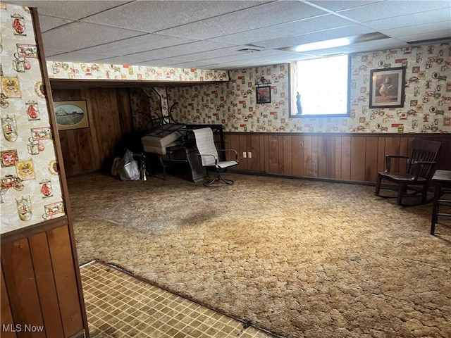 living area featuring carpet and a paneled ceiling