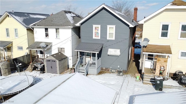 snow covered house with a storage unit