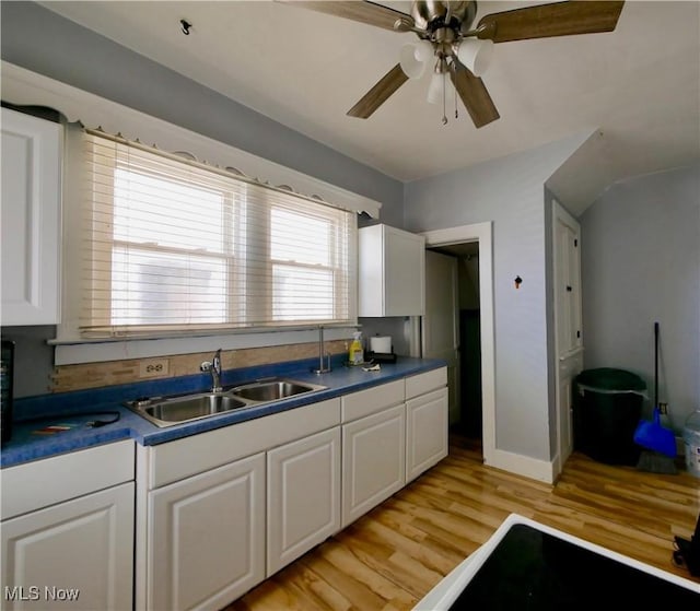 kitchen with light wood-type flooring, ceiling fan, white cabinetry, and sink