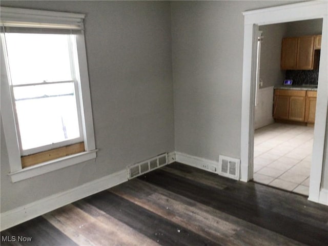 empty room with a healthy amount of sunlight and dark hardwood / wood-style floors