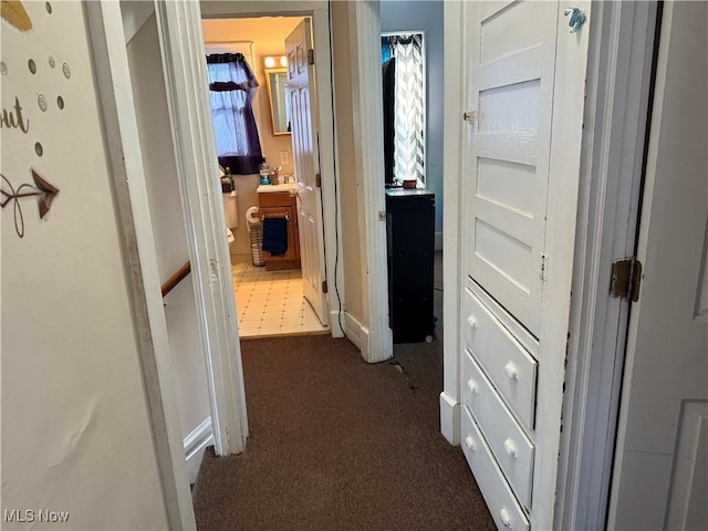 hallway with a wealth of natural light and dark colored carpet