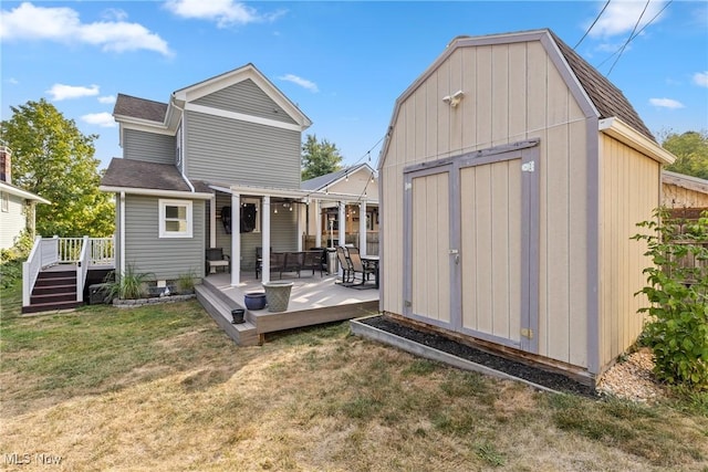 rear view of property with a wooden deck, a lawn, and a storage unit