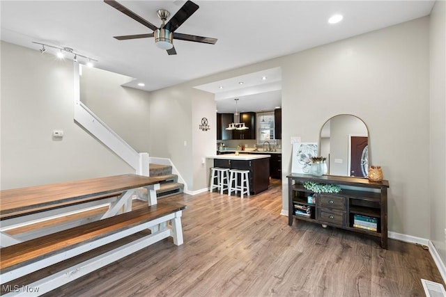 interior space featuring ceiling fan, rail lighting, wood-type flooring, and sink