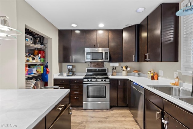 kitchen with decorative light fixtures, sink, light wood-type flooring, stainless steel appliances, and dark brown cabinets