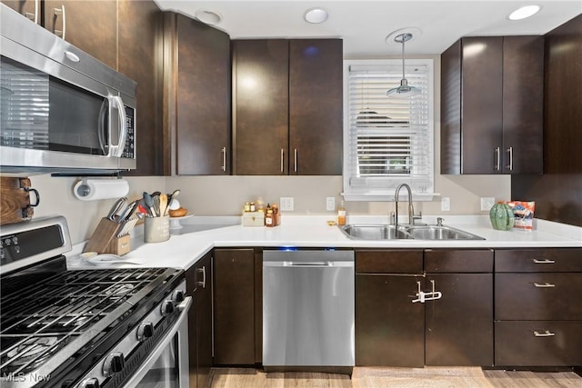 kitchen featuring dark brown cabinetry, appliances with stainless steel finishes, sink, and pendant lighting