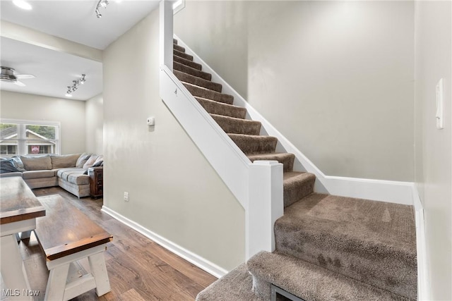 stairs with ceiling fan, track lighting, and hardwood / wood-style flooring