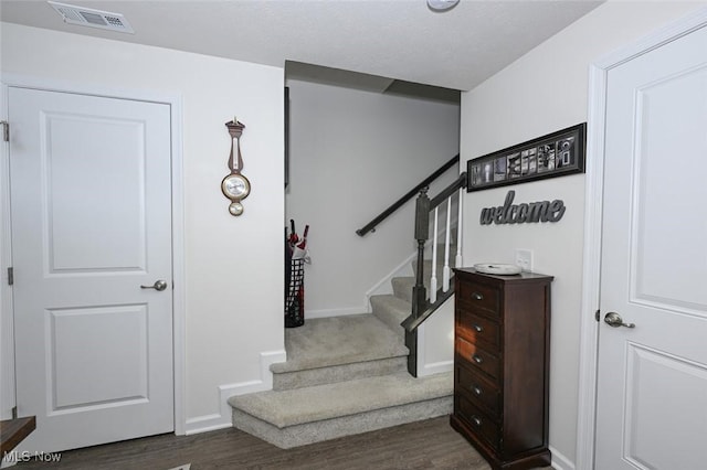 stairs with hardwood / wood-style floors and a textured ceiling