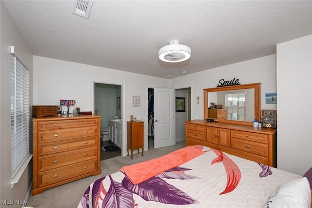 carpeted bedroom with a textured ceiling and ensuite bath