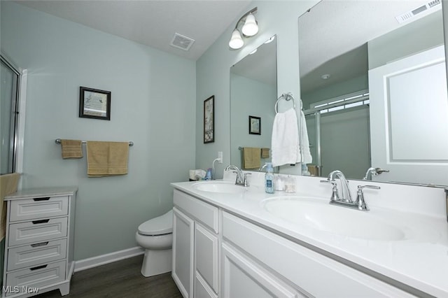 bathroom featuring a shower with door, vanity, wood-type flooring, and toilet