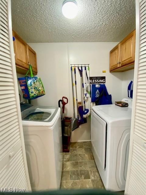 washroom with cabinets, a textured ceiling, and separate washer and dryer