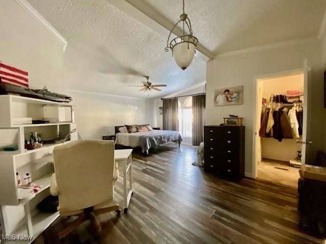 bedroom with a textured ceiling, a walk in closet, dark hardwood / wood-style floors, ornamental molding, and vaulted ceiling