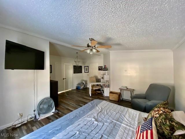 bedroom with a textured ceiling, ceiling fan, crown molding, and dark hardwood / wood-style floors