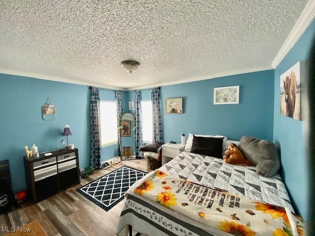 bedroom with dark wood-type flooring, a textured ceiling, and ornamental molding