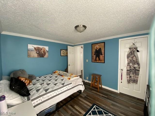 bedroom with dark wood-type flooring, a textured ceiling, and ornamental molding