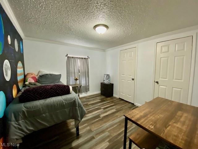 bedroom featuring hardwood / wood-style flooring, a textured ceiling, and ornamental molding