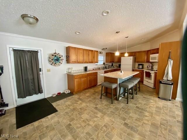 kitchen featuring a kitchen island, a kitchen bar, white appliances, hanging light fixtures, and a textured ceiling