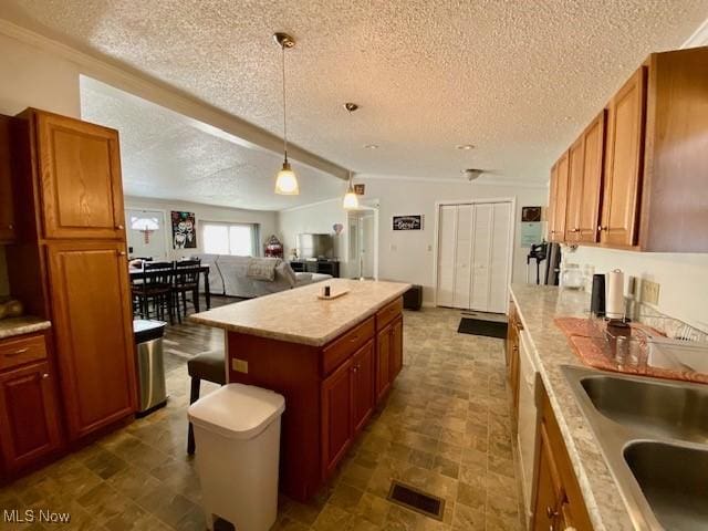 kitchen featuring sink, pendant lighting, a textured ceiling, and a center island