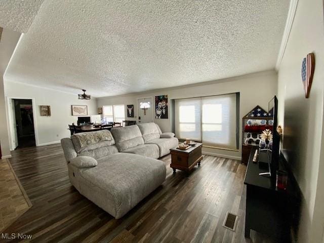 living room with dark wood-type flooring, a textured ceiling, and ornamental molding