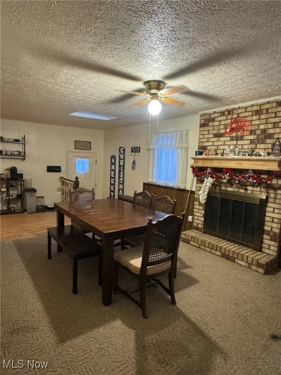 dining space featuring a brick fireplace, a textured ceiling, and ceiling fan