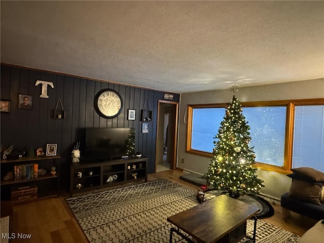 living room featuring wooden walls, a textured ceiling, and hardwood / wood-style floors