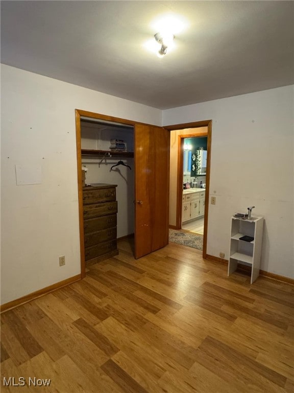 unfurnished bedroom featuring light wood-type flooring, a closet, and connected bathroom