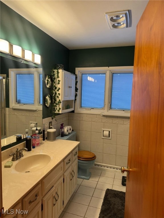 bathroom with tile walls, toilet, vanity, and tile patterned flooring