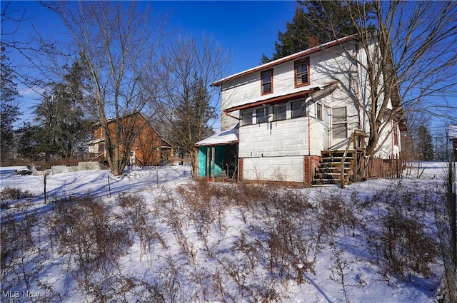 view of snow covered back of property