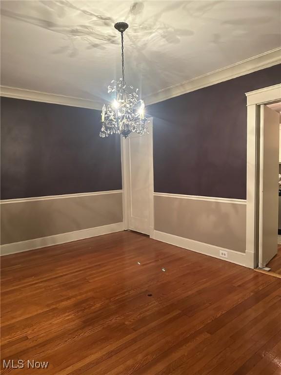 unfurnished dining area featuring an inviting chandelier, ornamental molding, and hardwood / wood-style floors