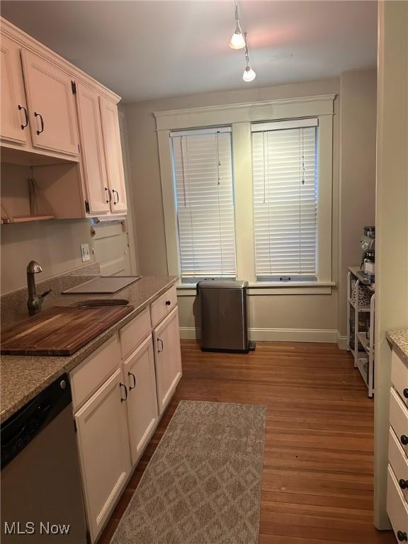 kitchen featuring white cabinets, dark hardwood / wood-style flooring, dark stone countertops, sink, and stainless steel dishwasher