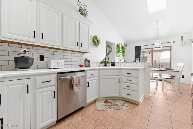 kitchen featuring lofted ceiling, light tile patterned floors, stainless steel dishwasher, and white cabinets