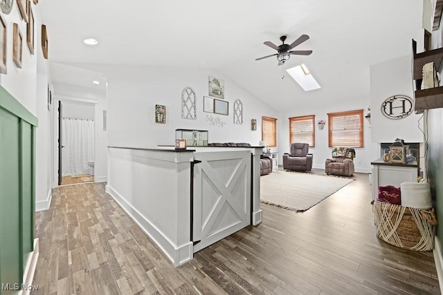 kitchen featuring ceiling fan, vaulted ceiling with skylight, and hardwood / wood-style floors