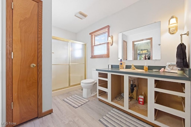 bathroom featuring toilet, vanity, a shower with door, and hardwood / wood-style floors