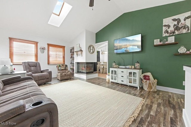 living room with a multi sided fireplace, dark hardwood / wood-style floors, vaulted ceiling with skylight, and ceiling fan