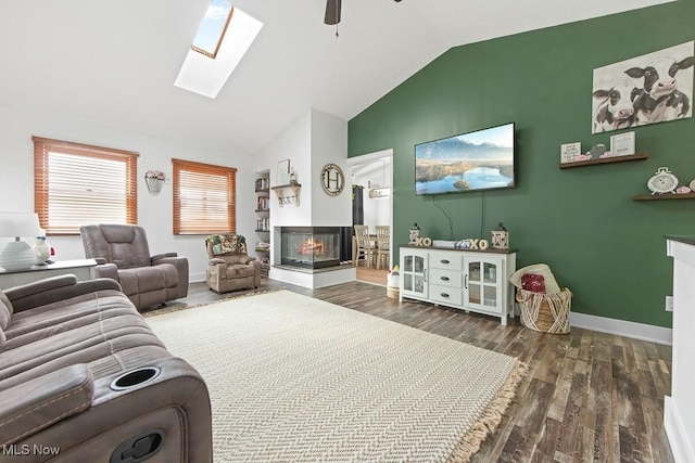 living room with dark hardwood / wood-style floors, a multi sided fireplace, vaulted ceiling with skylight, and ceiling fan