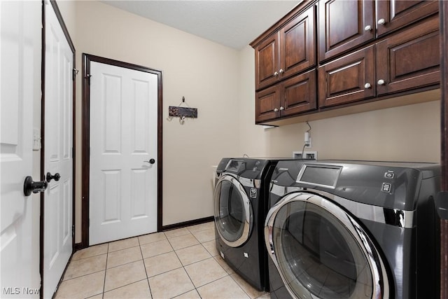 laundry room featuring cabinets, washing machine and dryer, and light tile patterned flooring