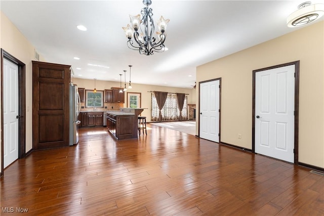 interior space featuring pendant lighting, stainless steel fridge, a center island, and hardwood / wood-style floors