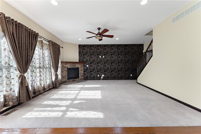 unfurnished living room featuring ceiling fan, carpet, and a fireplace