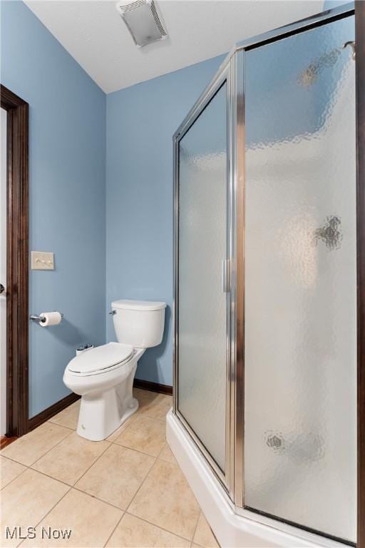 bathroom featuring tile patterned floors, toilet, and an enclosed shower