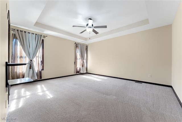 carpeted spare room featuring ceiling fan and a tray ceiling