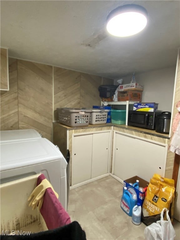 laundry room featuring wood walls, cabinets, and separate washer and dryer