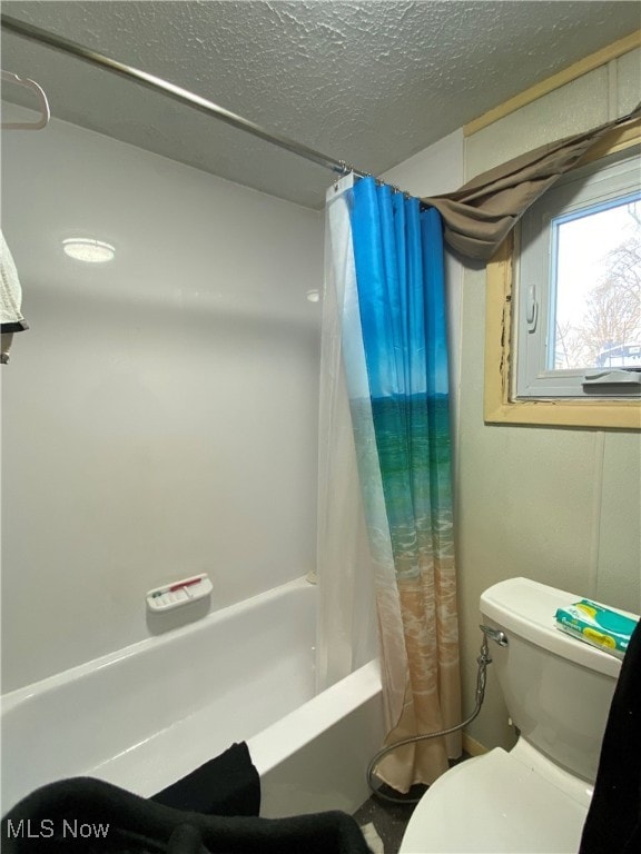 bathroom featuring toilet, shower / bath combo, and a textured ceiling