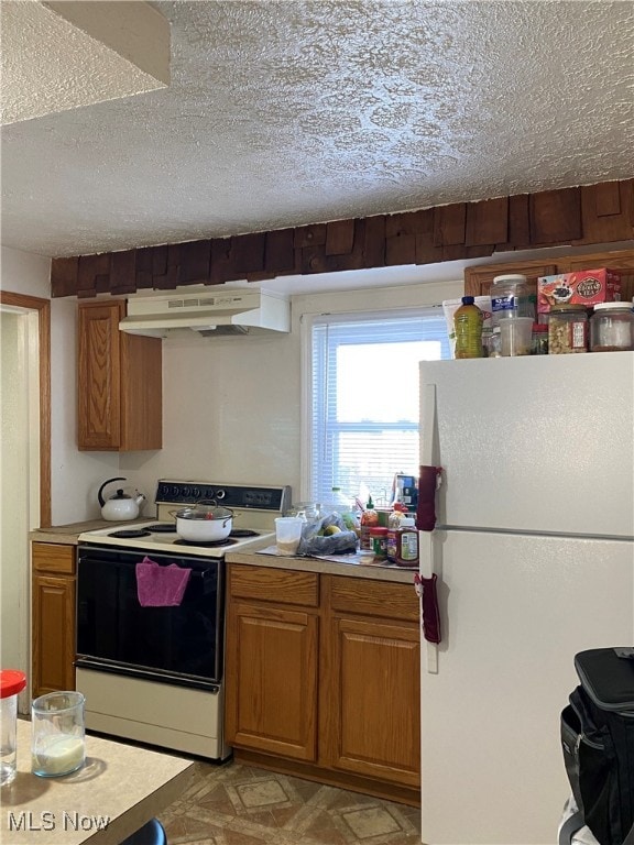 kitchen featuring a textured ceiling, white fridge, and range with electric stovetop