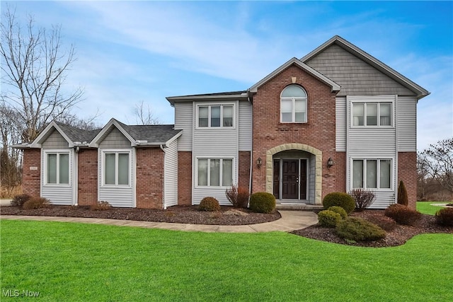 view of front facade with brick siding and a front yard