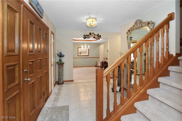 entryway featuring an inviting chandelier, stairs, a textured ceiling, and light tile patterned flooring