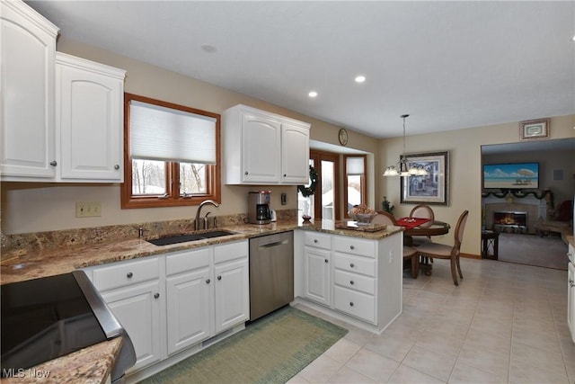 kitchen featuring pendant lighting, stainless steel dishwasher, white cabinets, a sink, and a peninsula