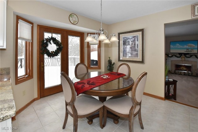 dining area with an inviting chandelier, a fireplace, baseboards, and light tile patterned flooring