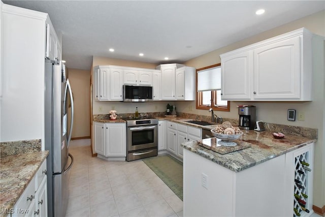 kitchen featuring stone countertops, white cabinets, appliances with stainless steel finishes, a sink, and recessed lighting