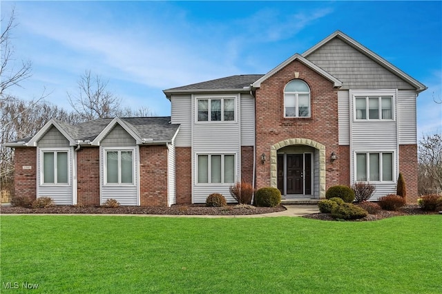 view of front of property with brick siding, a front lawn, and roof with shingles