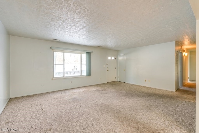 unfurnished room with carpet and a textured ceiling